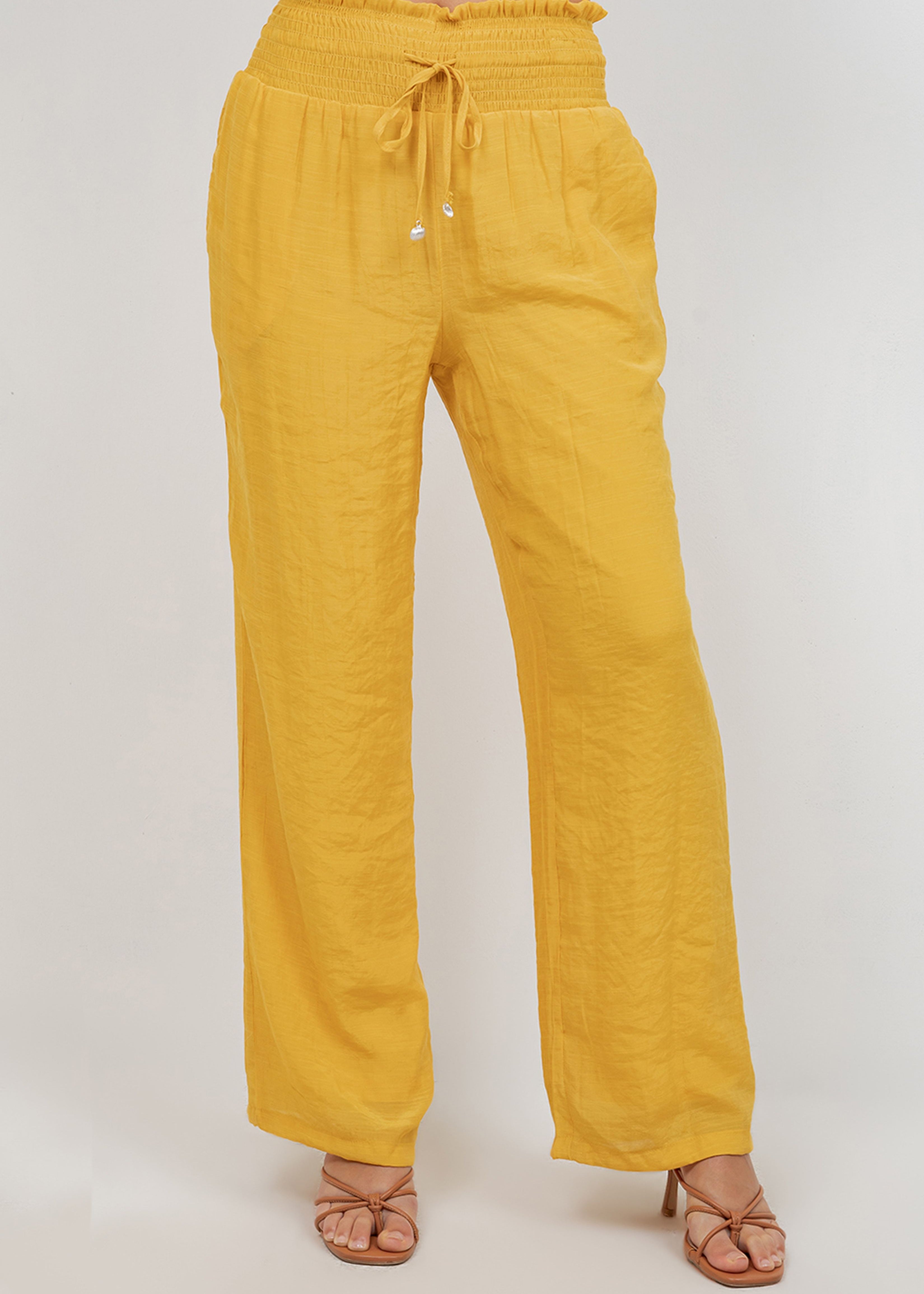 Front view of model wearing yellow Ladies Smocked Waist Drawstring Palazzo Pants with heeled sandals.