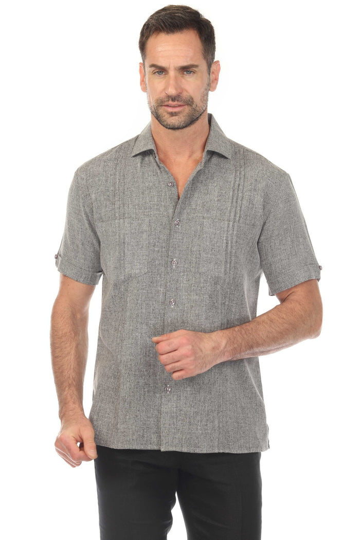 A man poses wearing a white Men’s Classic Two-Pocket Guayamisa Shirt with Pleats and grey pants.