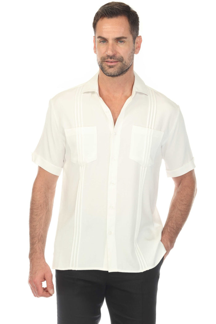 A man poses wearing a white Men’s Classic Two-Pocket Guayamisa Shirt with Pleats and grey pants.