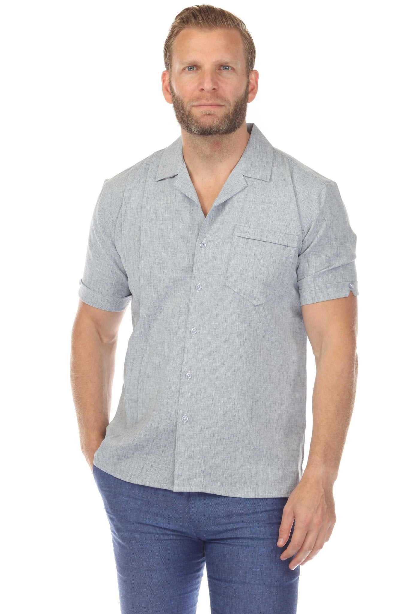 A man wears a light gray, short-sleeve Menâ€™s Retro Cuban Shirt with a pocket and pleating detail.