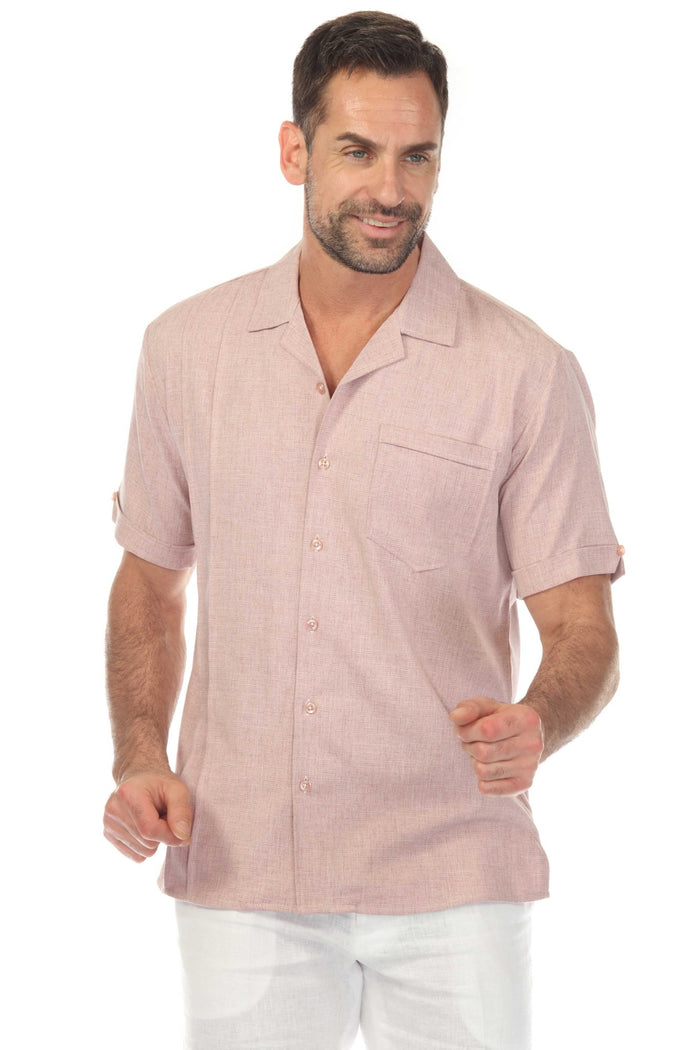 A man wears a pink Menâ€™s Retro Cuban Shirt with pleating and one pocket, holding sunglasses outside.