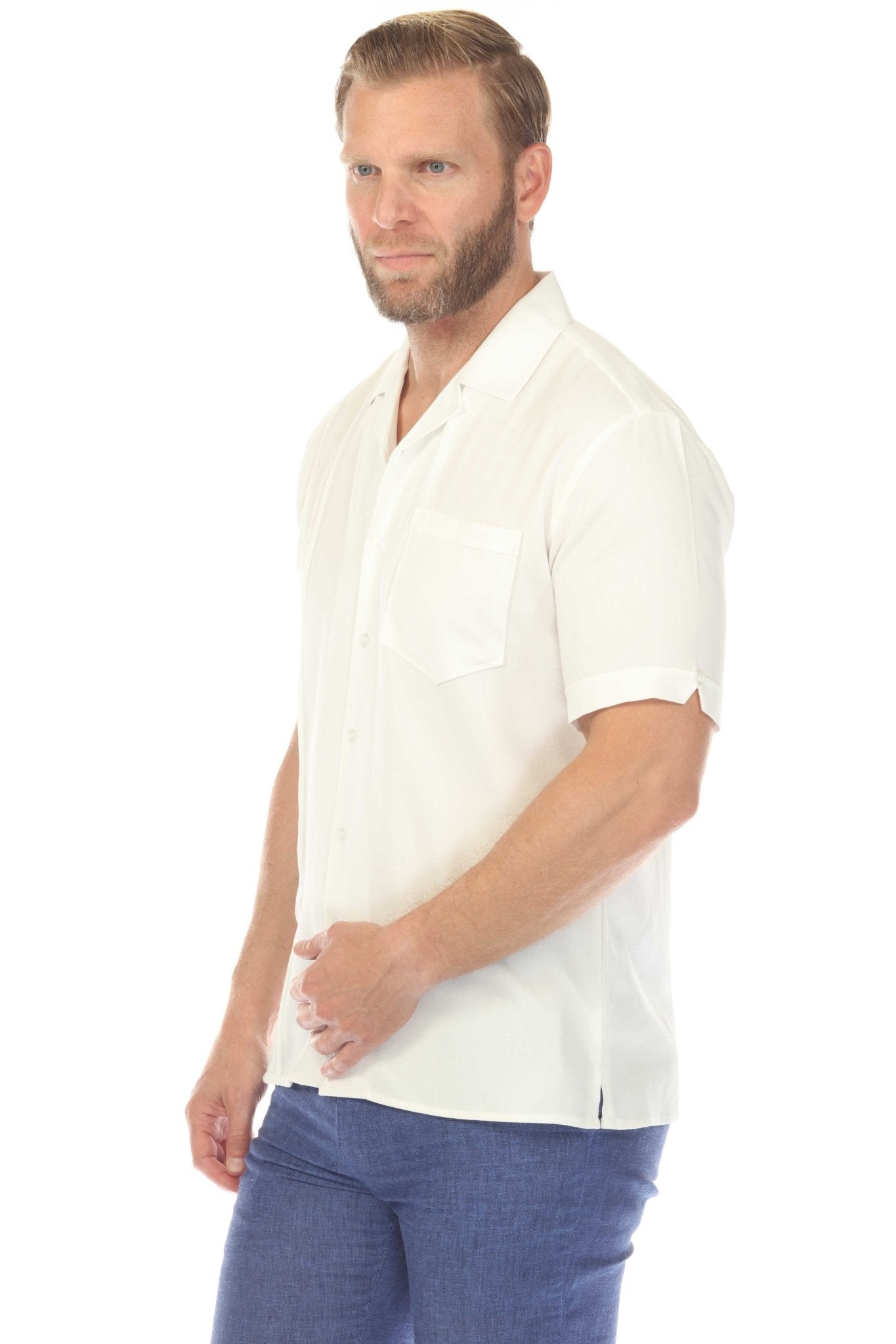 Side view of a man wearing the Menâ€™s Retro Cuban Shirt, which is white with a pocket and pleating, and blue linen pants.