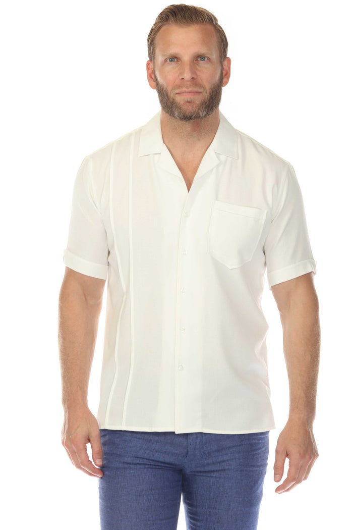 A man wears a pink Menâ€™s Retro Cuban Shirt with pleating and one pocket, holding sunglasses outside.