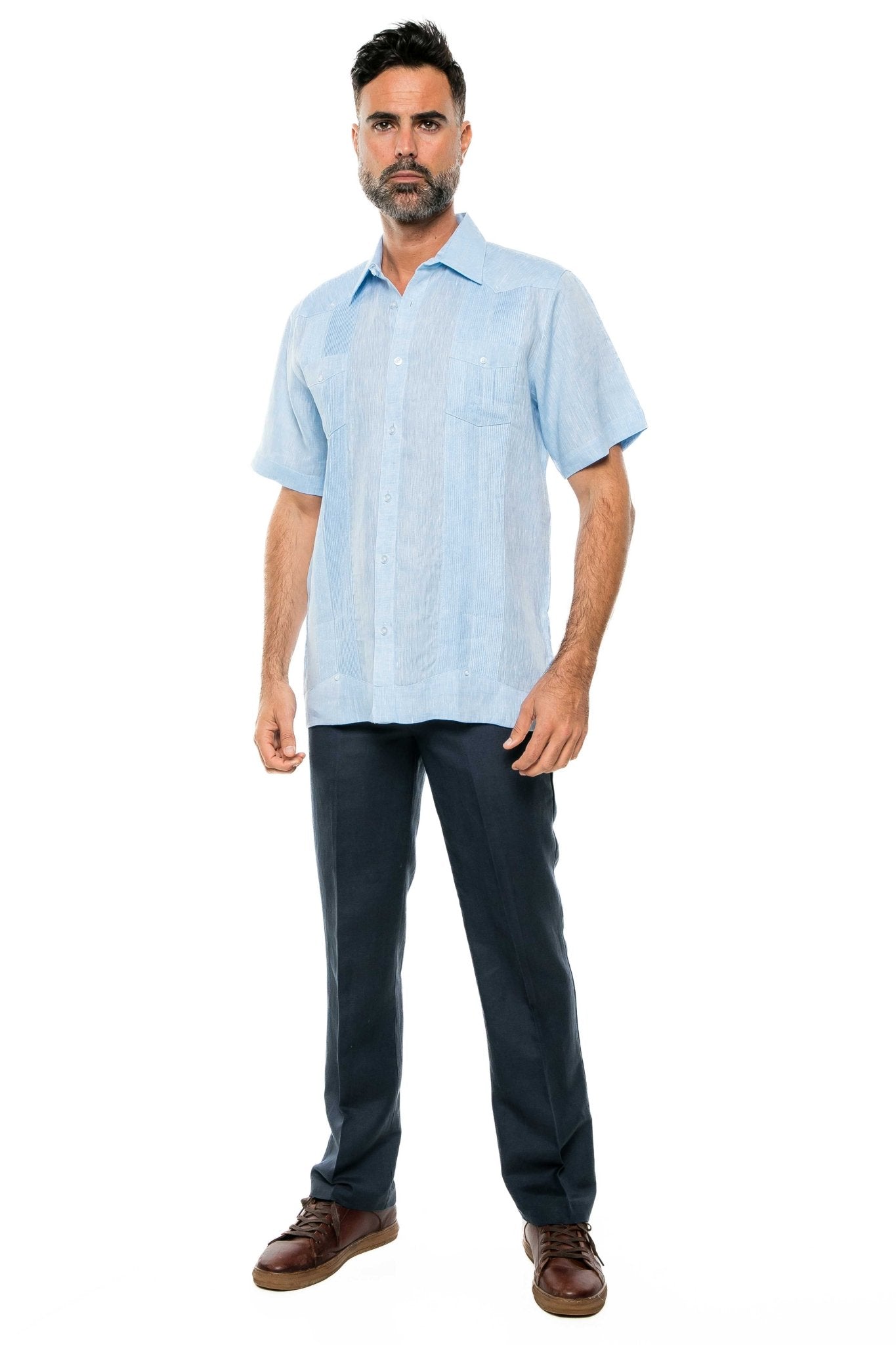 Full-length shot of a man wearing a light blue Yarn Dye 100% Linen Two Pocket Guayabera Short Sleeve with dark slacks and brown shoes.
