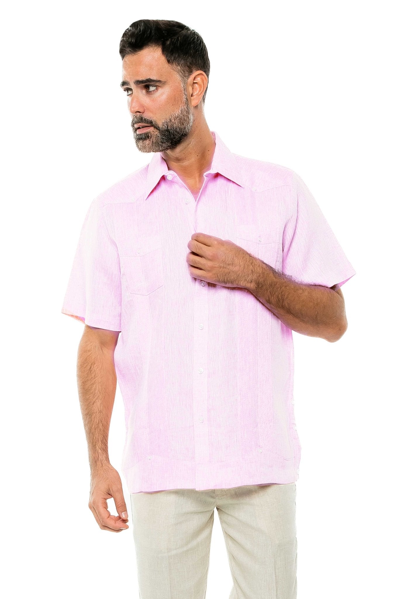 A man wears a pink Yarn Dye 100% Linen Two Pocket Guayabera Short Sleeve shirt and tan pants, posed on a white background.