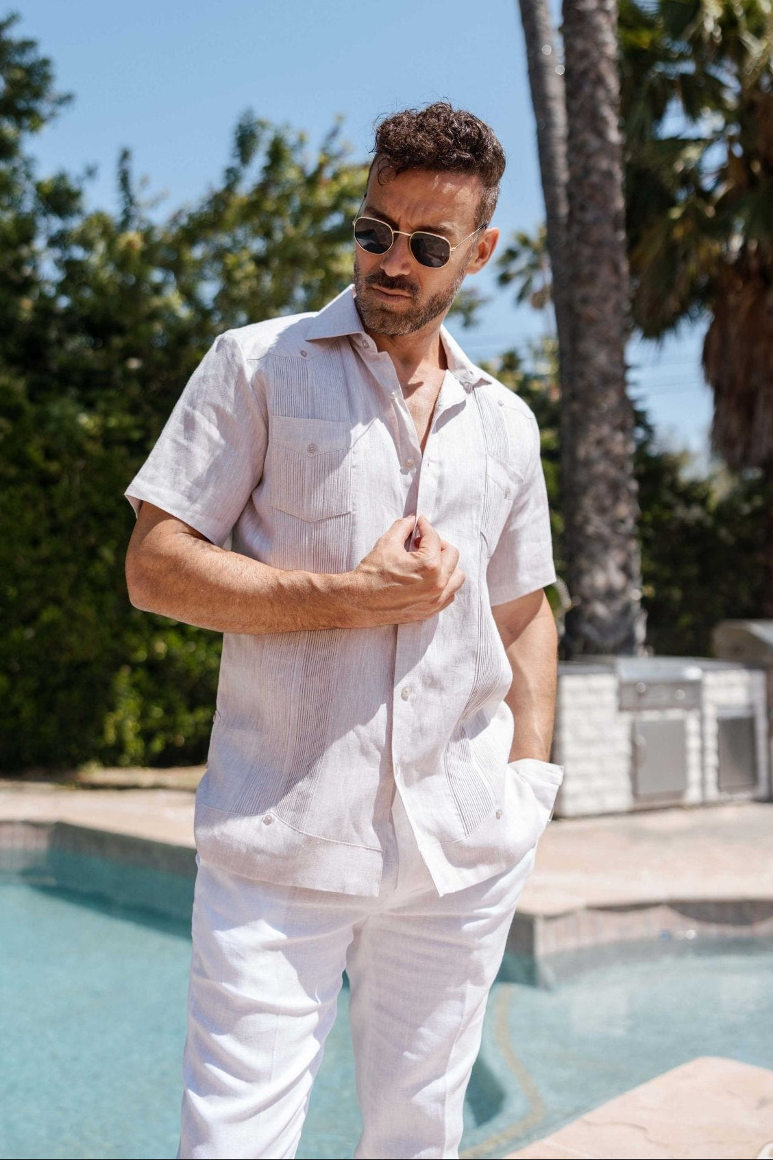 A man models the yarn dye 100% linen two pocket guayabera short sleeve shirt in white stripe, with two front pockets.