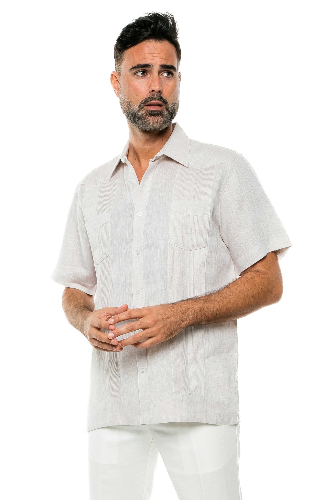 A man models the yarn dye linen guayabera shirt in off-white, featuring short sleeves and two visible front pockets.