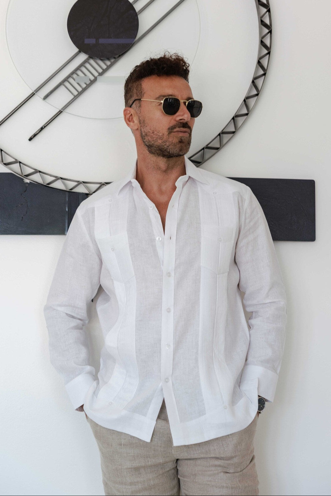 A person wears a white linen long-sleeve, two-pocket Guayabera shirt, open at the collar.