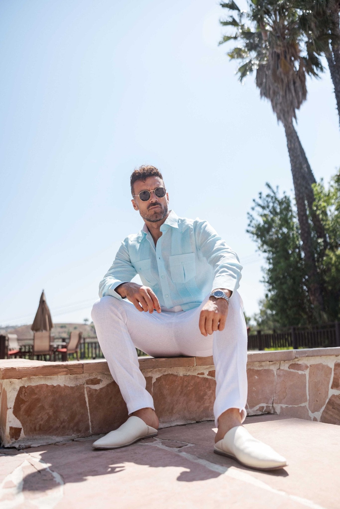 Low angle shot of a person wearing a light blue long sleeve 100% Linen Contrast Panel Guayabera Shirt.