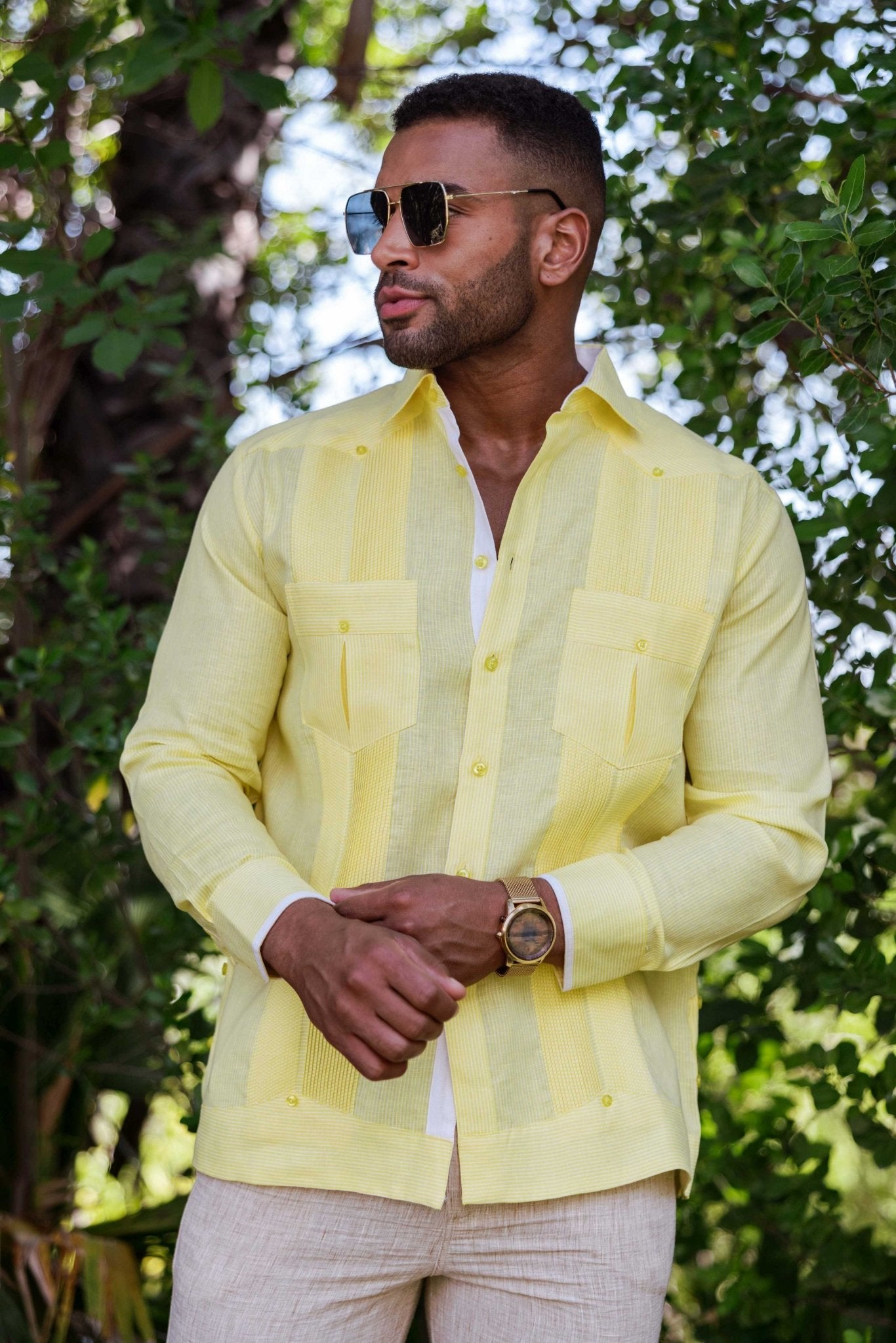 Model wears a yellow 100% Linen Contrast Panel Guayabera Shirt, long sleeve, with white undershirt and khaki pants.
