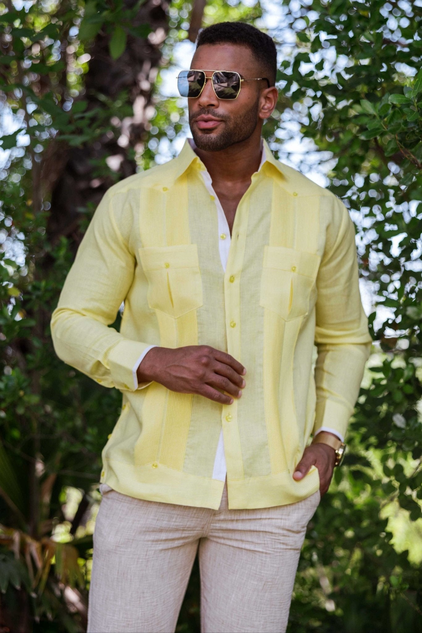 Man wears a yellow 100% Linen Contrast Panel Guayabera Shirt with long sleeves and front pockets.