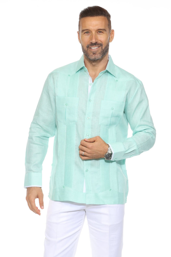 A man wears a blue striped 100% Linen Contrast Panel Guayabera Shirt with long sleeves and white linen pants.