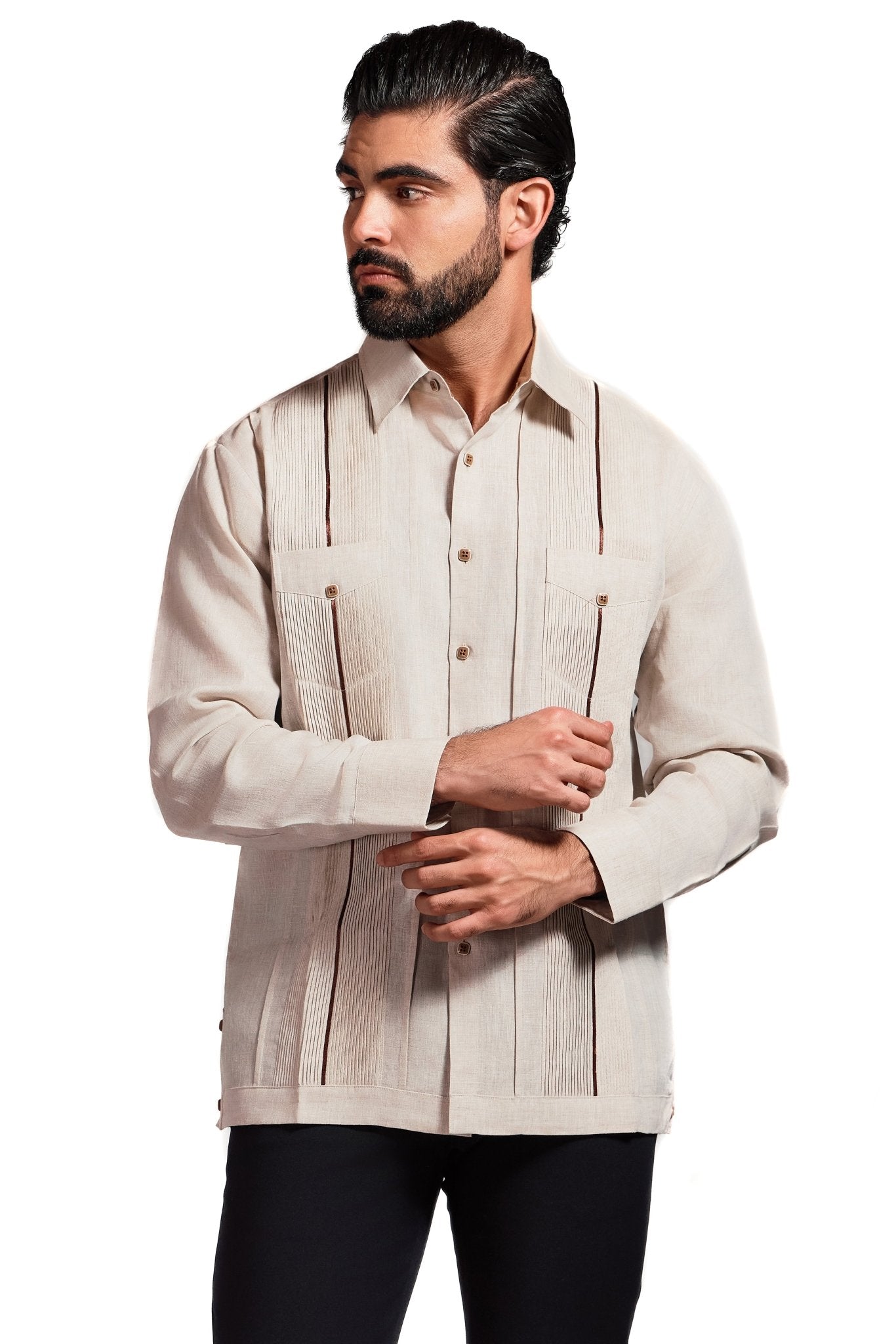 A man models the long-sleeve linen Guayabera shirt in tan with brown trim, looking left.