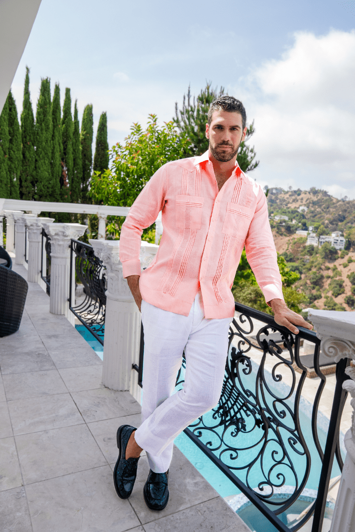 Men's salmon linen embroidered guayabera long sleeve with white linen pants and loafers on a balcony by the pool