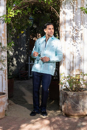 Full lifestyle shot of the light blue Men’s Long Sleeve Linen Guayabera Shirt paired with navy trousers, ideal for rooftop events and destination weddings.