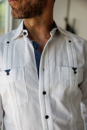 Extreme close-up of a white Men’s Long Sleeve Linen Guayabera Shirt focusing on the blue printed trim inside the collar and the intricate pleated detailing.