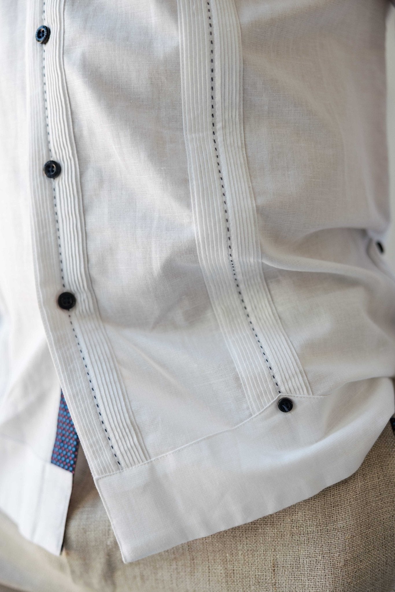 Detailed close-up of the classic pleated front and contrast printed trim on the hem of a white Men's Long Sleeve Linen Guayabera Shirt.
