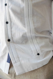 Detailed close-up of the classic pleated front and contrast printed trim on the hem of a white Men's Long Sleeve Linen Guayabera Shirt.