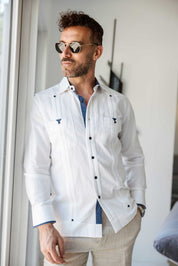 A man wearing a white Men’s Long Sleeve Linen Guayabera Shirt and sunglasses, perfect for beach weddings and warm tropical evenings.