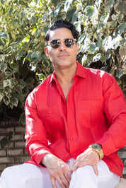 A man in a red Yarn Dyed Linen Guayabera with pleats and two pockets.