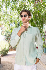 Man wearing a light green "Yarn Dyed Linen Guayabera" shirt with multi pleats and two pockets.