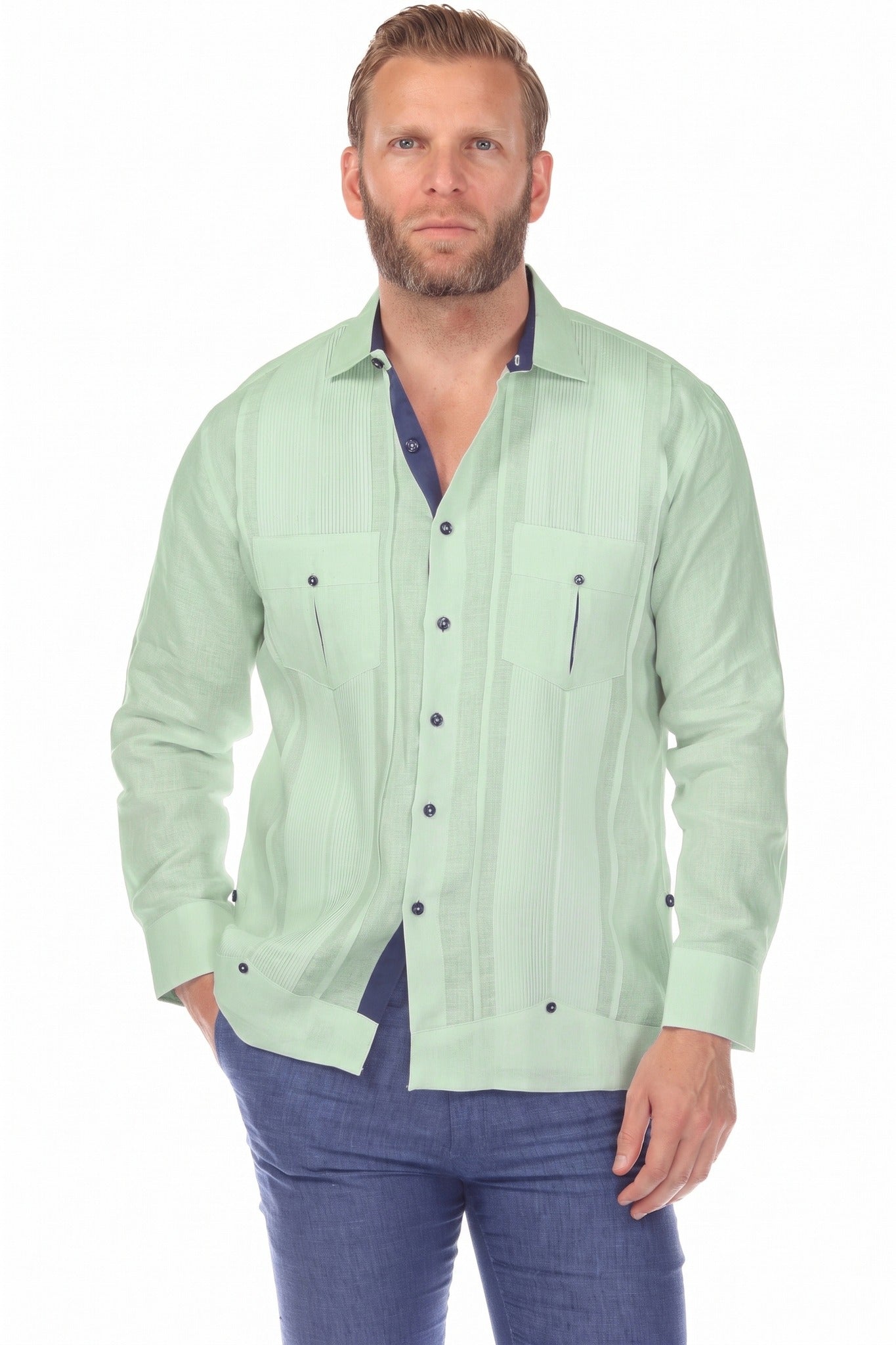 Front view of a man wearing the sage green 100% Linen Contrast Panel Guayabera Shirt Long Sleeve with navy trim, hand in pocket.