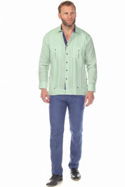 Full-length view of a man wearing the sage green 100% Linen Contrast Panel Guayabera Shirt Long Sleeve with blue pants.