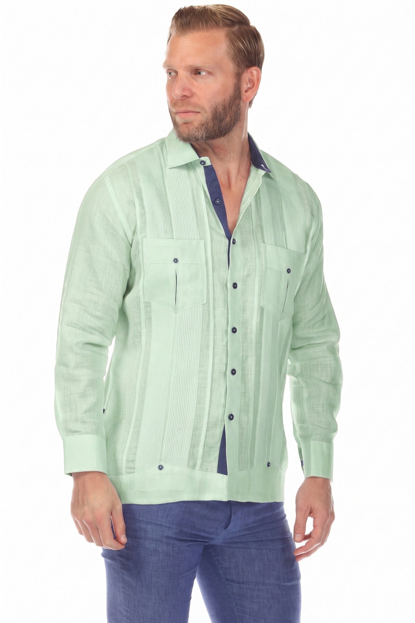 A man wears the sage green 100% Linen Contrast Panel Guayabera Shirt, long-sleeved, buttoned, with navy trim.
