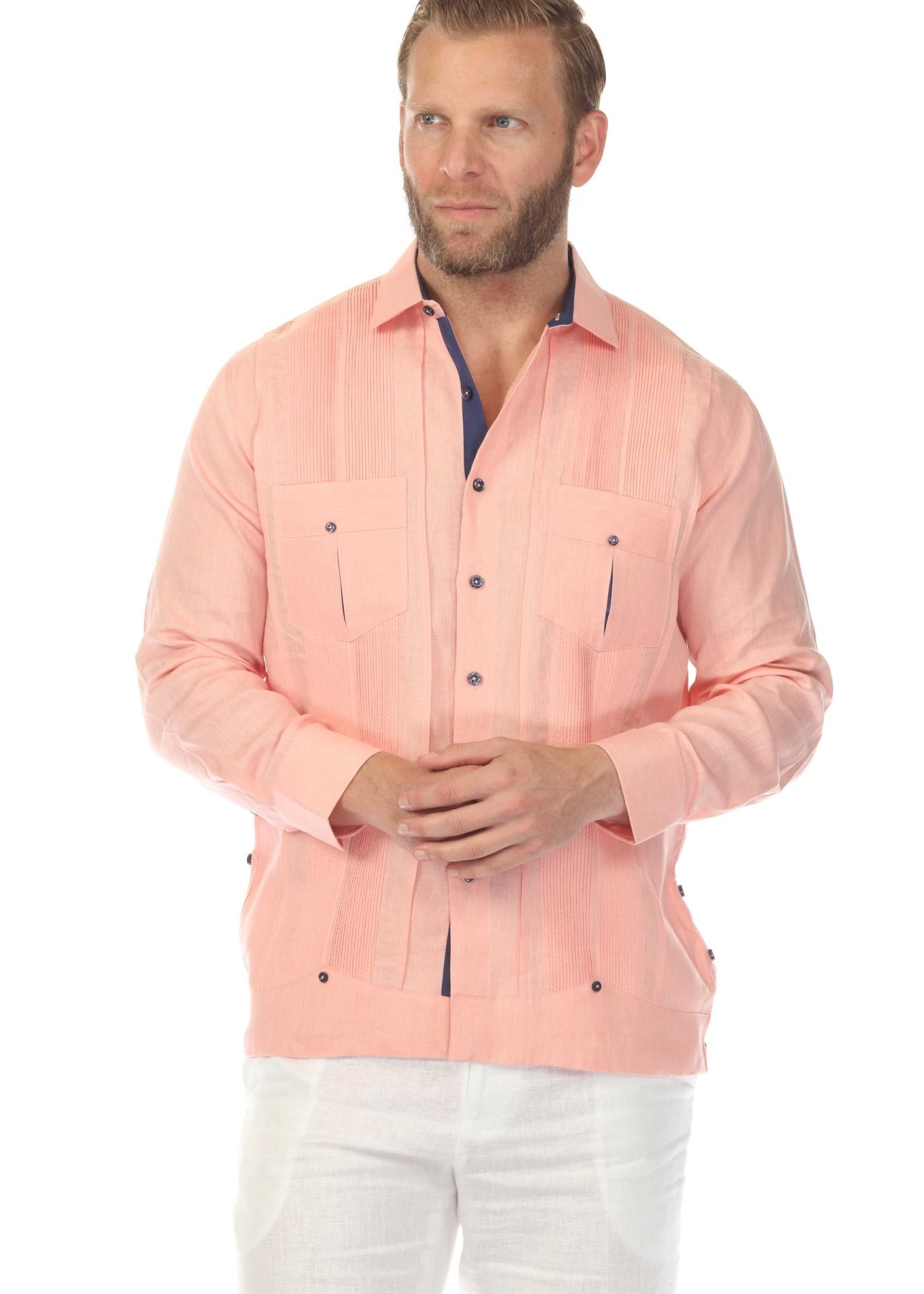 Men's salmon linen guayabera shirt half-body view, model looking away showing tailored fit with navy buttons and chest pockets, clean white studio background
