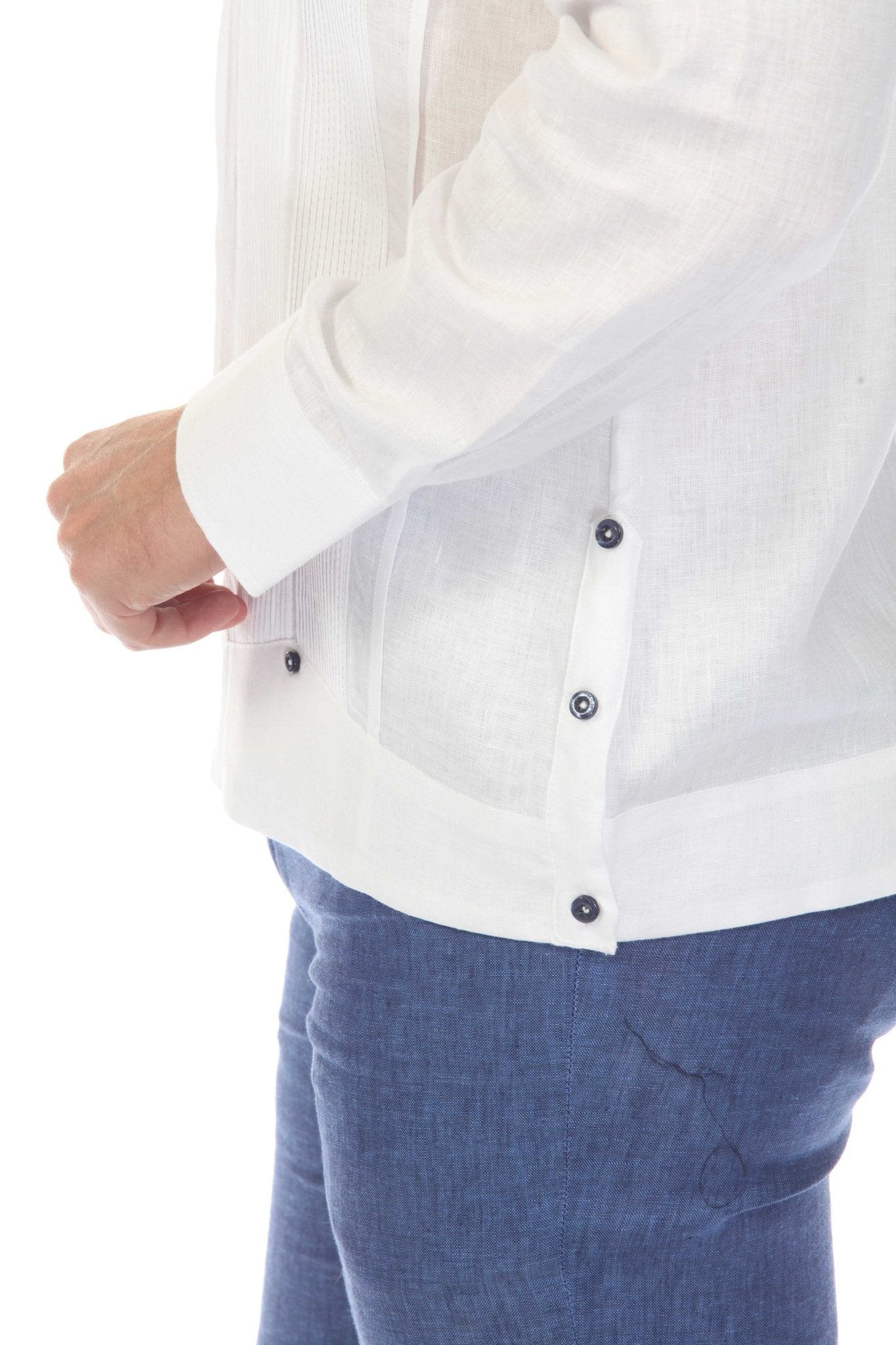 Side detail close-up of men's white linen guayabera shirt showing navy side buttons, long sleeve cuff, and breathable linen fabric hem on white studio background