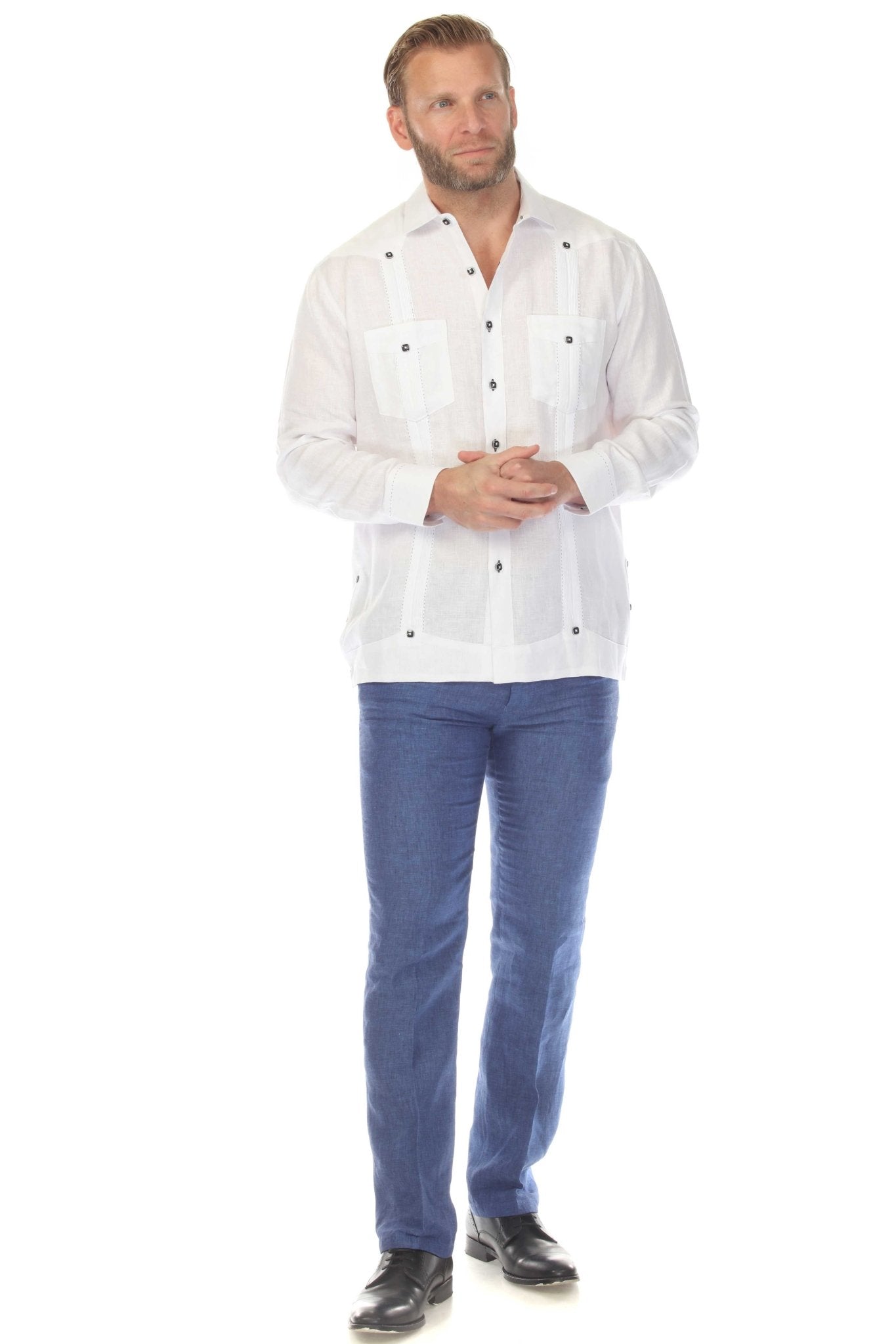 Full-shot of a man wearing a white 100% Linen Contrast Panel Guayabera Shirt, long sleeved, with blue jeans and black shoes.