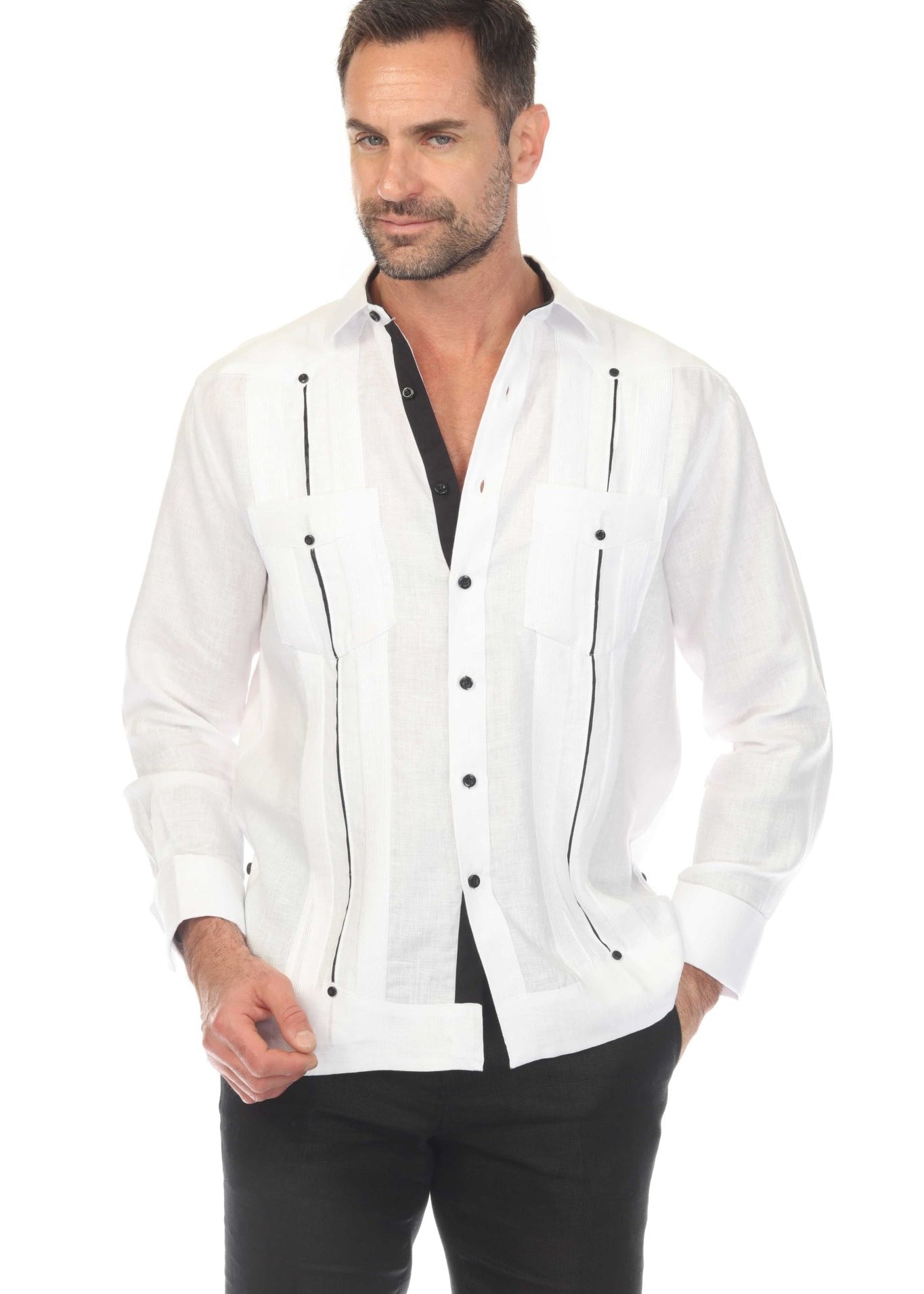 A man wears an open white linen guayabera with black contrast satin taping and French cuffs.