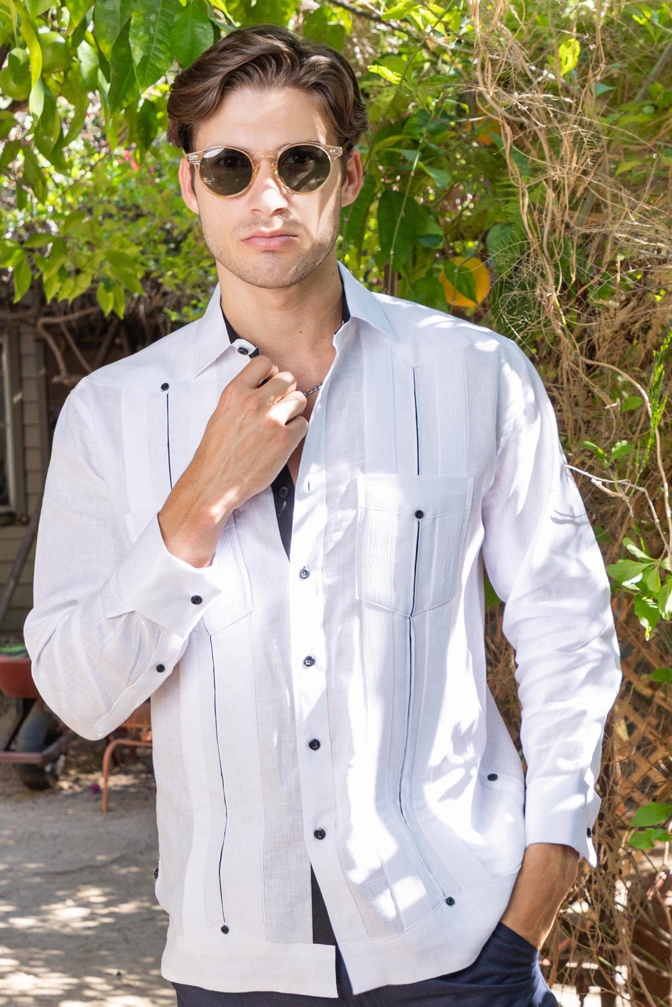 Man wears a white 100% Linen Contrast Panel Guayabera Shirt Long Sleeve with black buttons and decorative stitching.