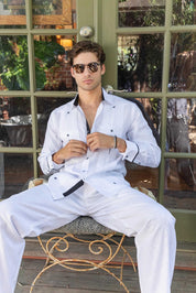 Person in white 100% Linen Contrast Panel Guayabera Shirt, long sleeve, seated, unbuttoning shirt to reveal contrast panel.