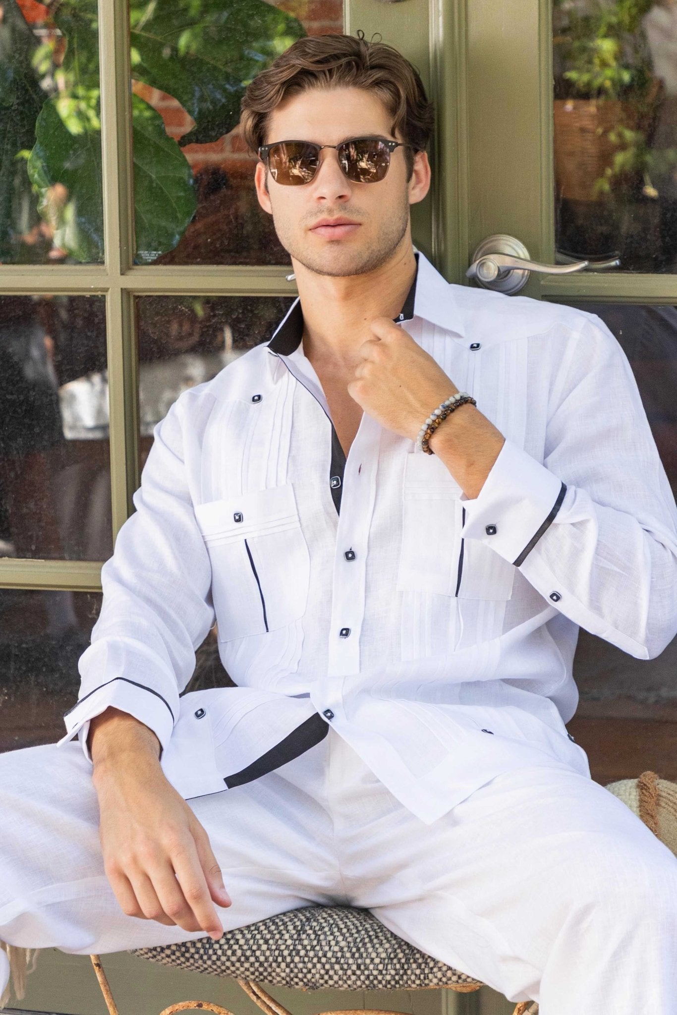 Model wears a white, long sleeve 100% Linen Contrast Panel Guayabera Shirt, unbuttoned at the top, with dark trim.