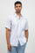 Man wearing a white short-sleeve shirt and light blue jeans against a plain background