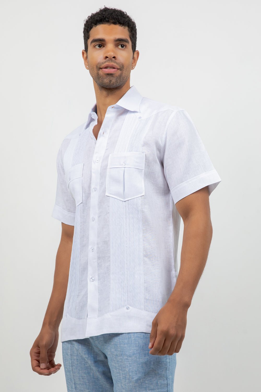 Man wearing a white short-sleeve shirt with a pocket on a plain background