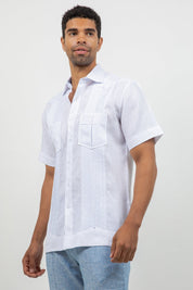 Man wearing a white short-sleeve shirt with a pocket on a plain background