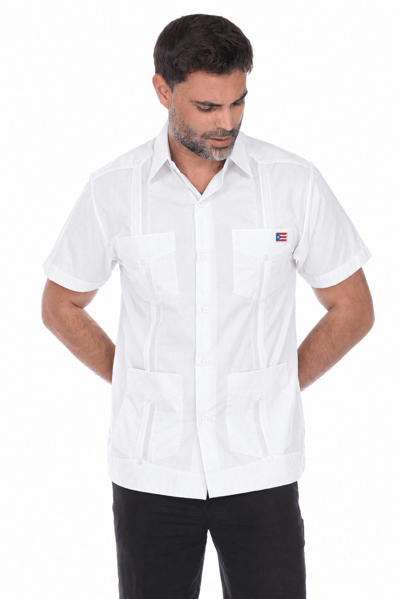Man wearing the white Limited Edition guayabera with an embroidered Puerto Rico flag patch on the left chest pocket, front view with black trousers