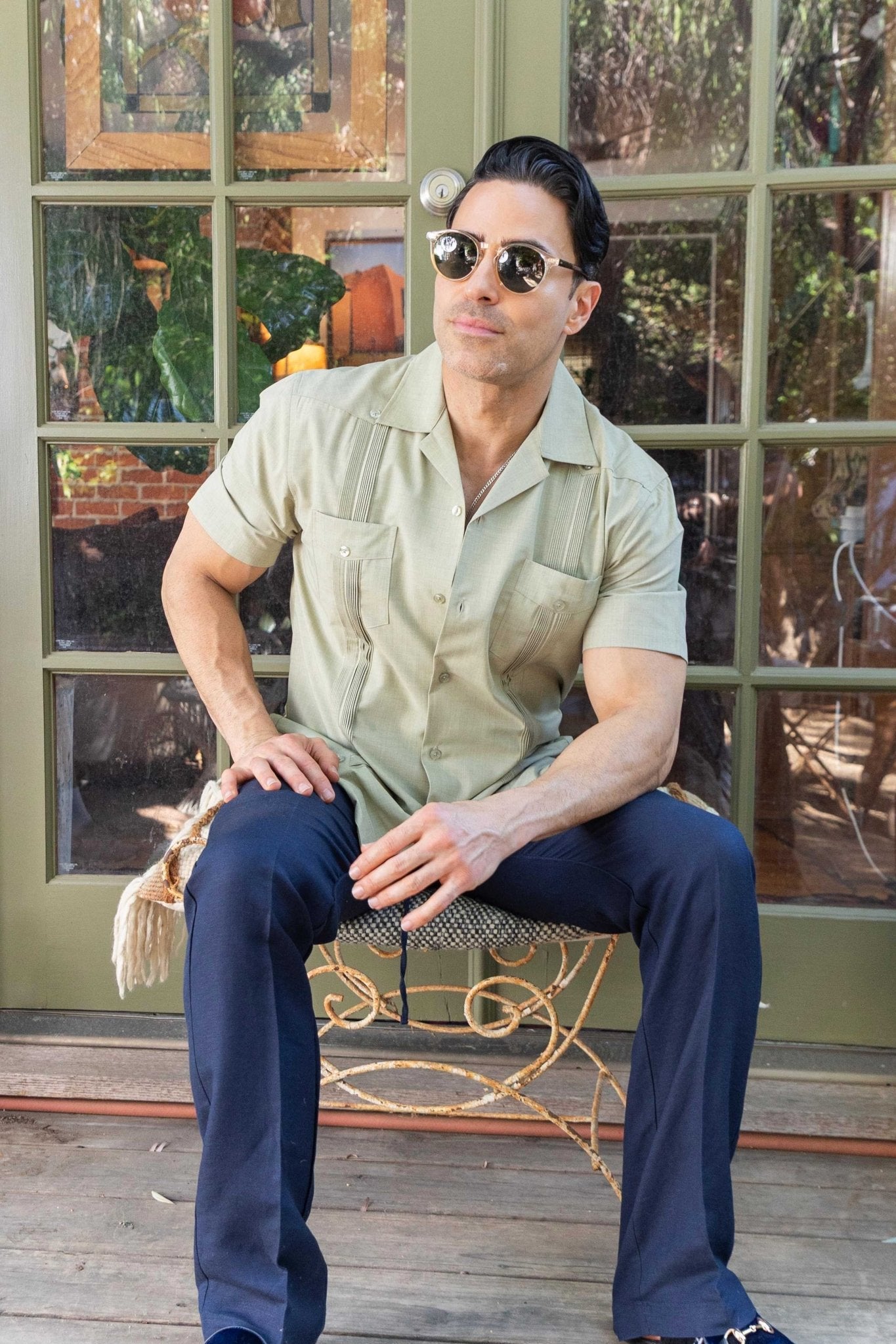 Man seated in a light green, two-pocket, pleated Men's Two-Pocket Cross-Dye Guayamisa Shirt.