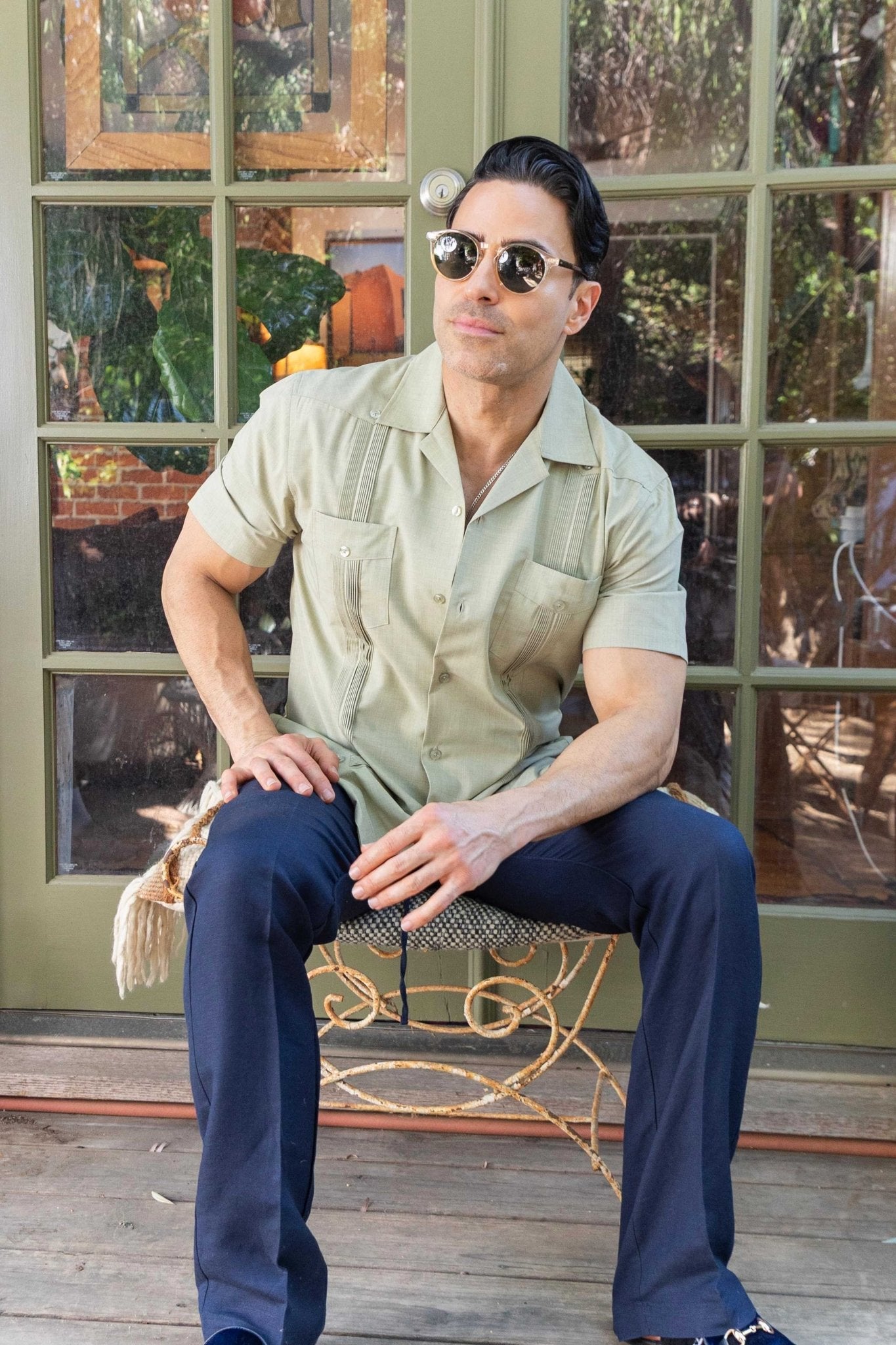 Man seated in a light green, two-pocket, pleated Men's Two-Pocket Cross-Dye Guayamisa Shirt.