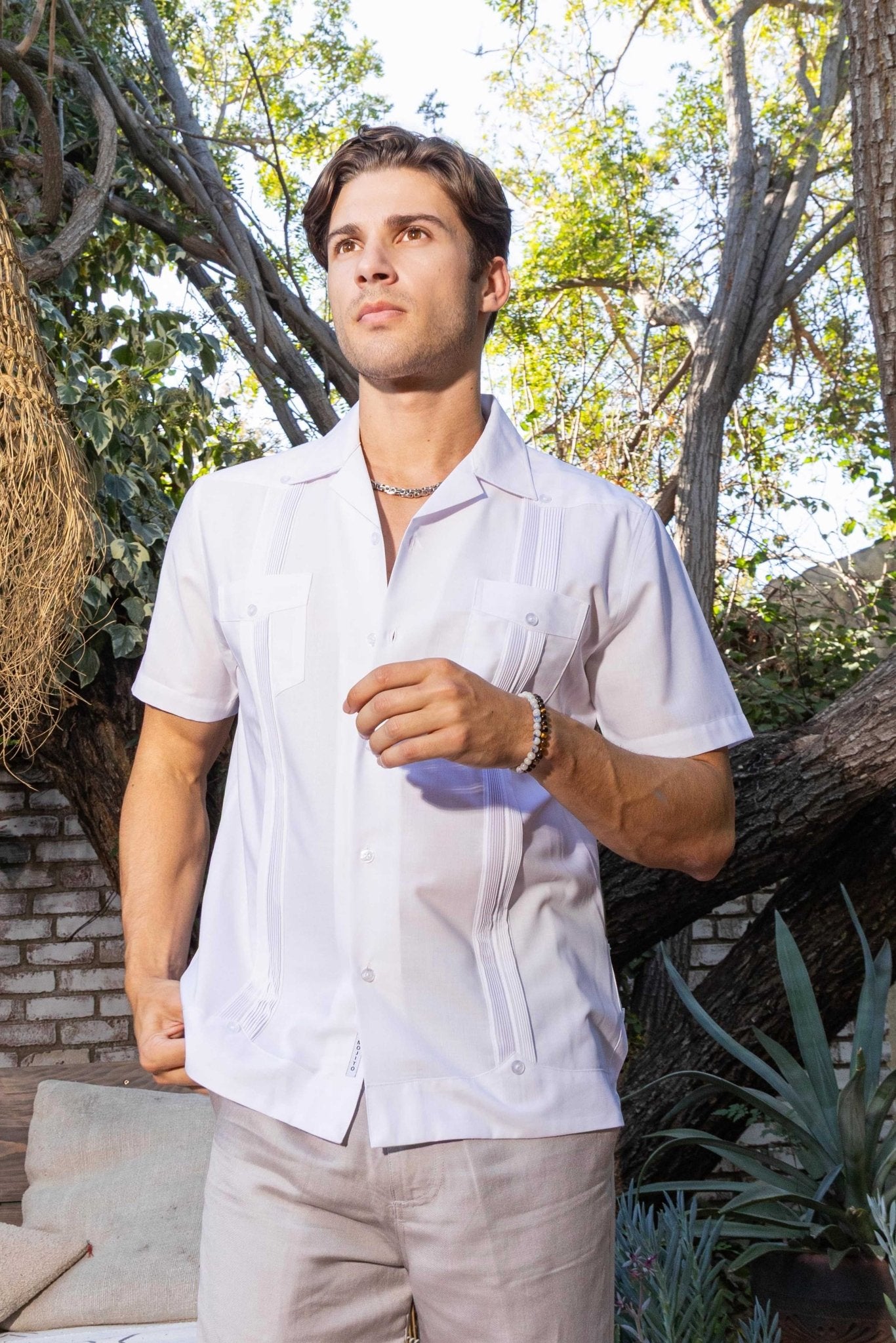 A man wears a white, pleated Men’s Two-Pocket Cross-Dye Guayamisa Shirt, shown from the front with two pockets.