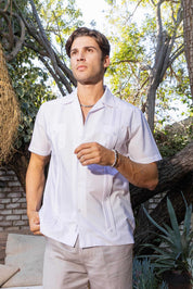 A man wears a white, pleated Men’s Two-Pocket Cross-Dye Guayamisa Shirt, shown from the front with two pockets.