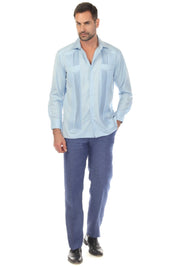 Full view of a man wearing a light blue, two-pocket, long sleeve Guayabera shirt with pick stitching.