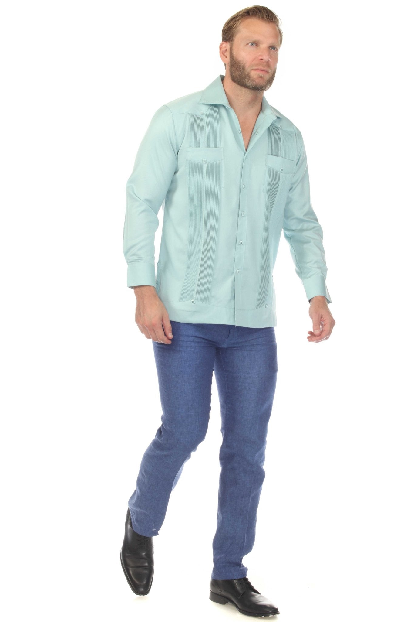 A man models the light teal Men’s Long Sleeve Two-Pocket Guayabera Shirt with pick stitching detail on the front panels.