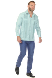 A man models the light teal Men’s Long Sleeve Two-Pocket Guayabera Shirt with pick stitching detail on the front panels.