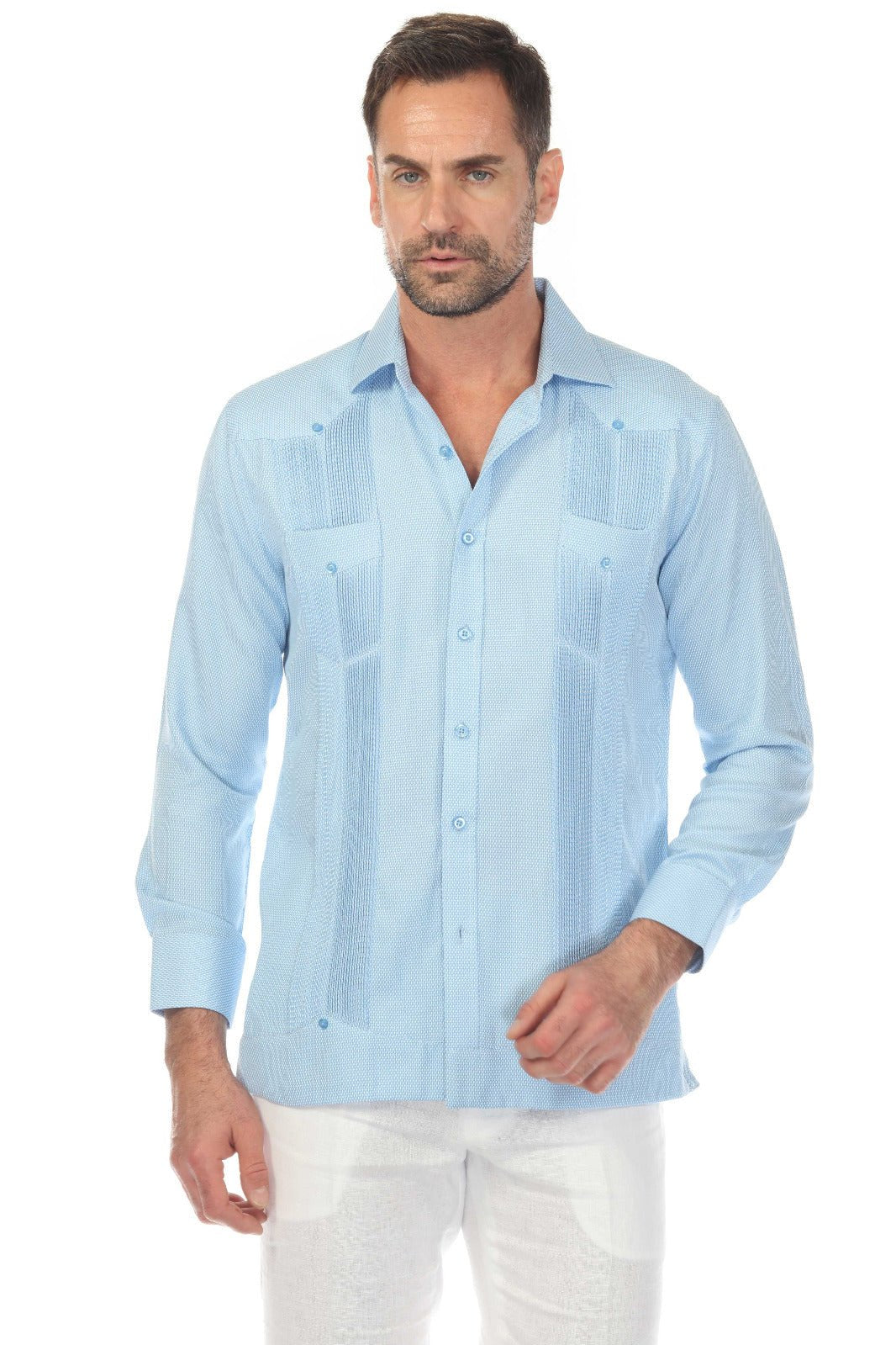 A man wears a light blue, diamond textured Men's Two-Pocket Guayabera tucked into white pants.