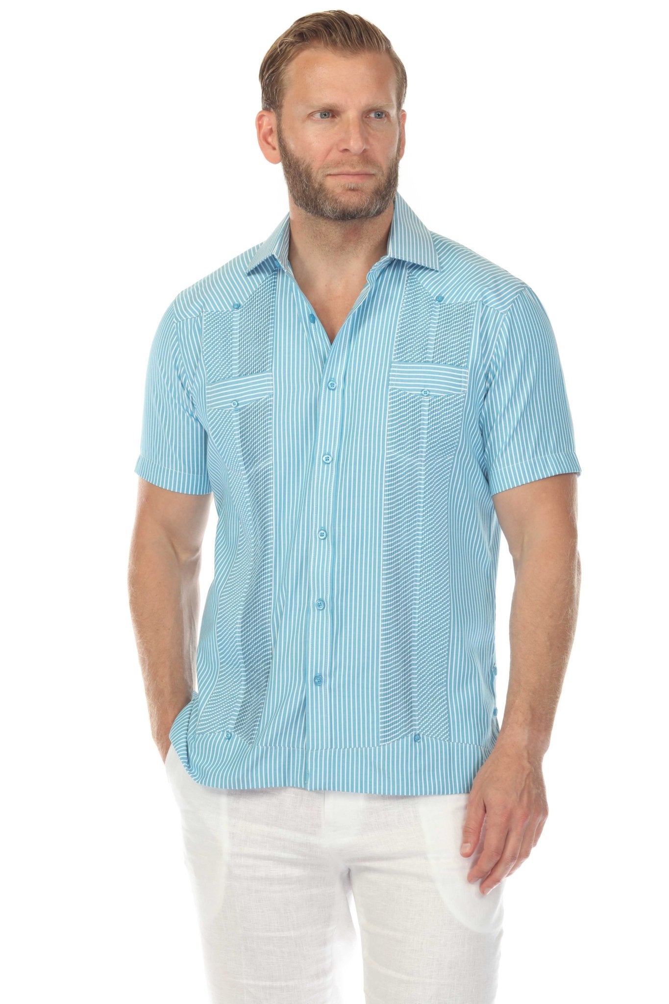 A man wears a blue, short-sleeved Men’s Two-Pocket Guayabera Shirt with Micro Textured Print and white pants.