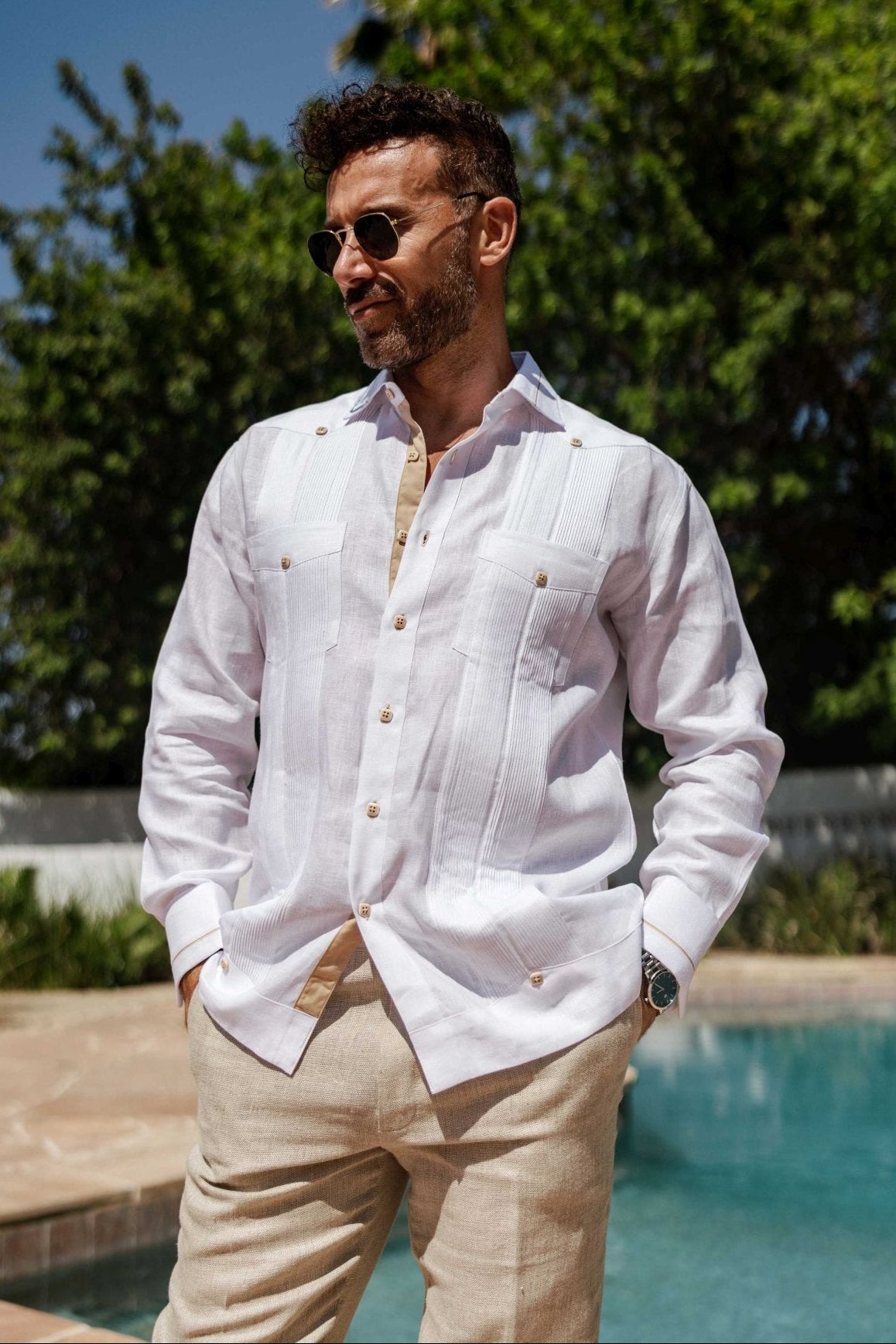 A man stands in a white Contrast Trim Linen Guayabera, showcasing the two pockets and long sleeves.