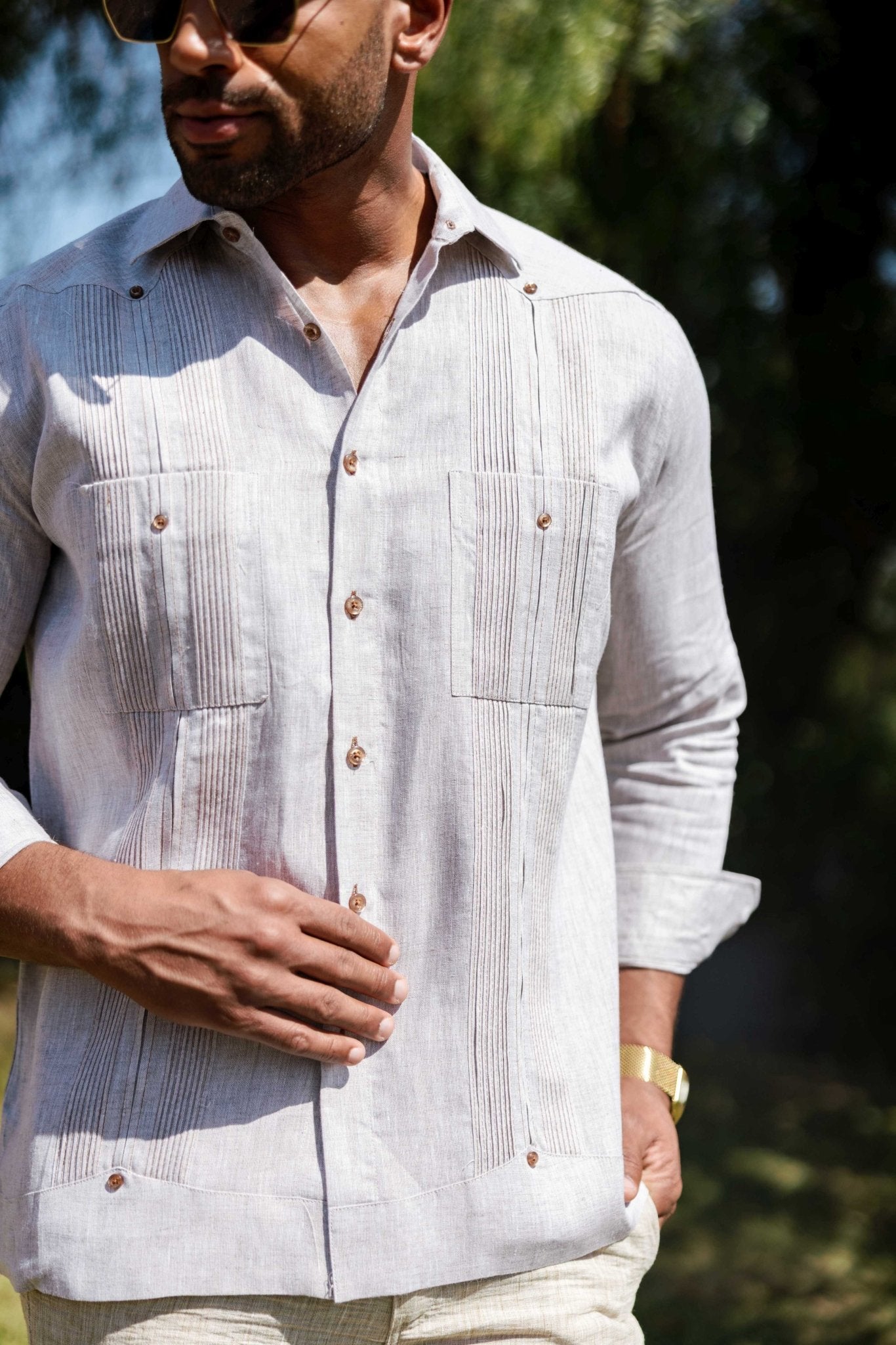 Close-up of a man modeling the linen guayabera shirt, long sleeve, in light gray with  heritage pleats.